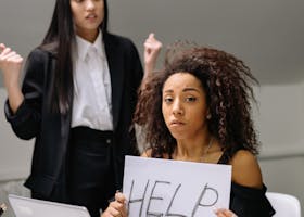 A woman holding a help sign, depicting workplace harassment in an office setting.